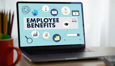 Laptop screen showing the text "EMPLOYEE BENEFITS" with various icons around it.