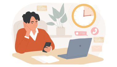 Person sitting at a desk with a smartphone, laptop, papers, and a clock showing 10:09.