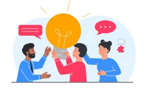 Illustration of three people—two appearing male and one appearing female—collaborating around a large glowing lightbulb icon, with speech bubbles and a puzzle piece symbol in the background. All wear casual long‑sleeve clothing in blue and red tones.